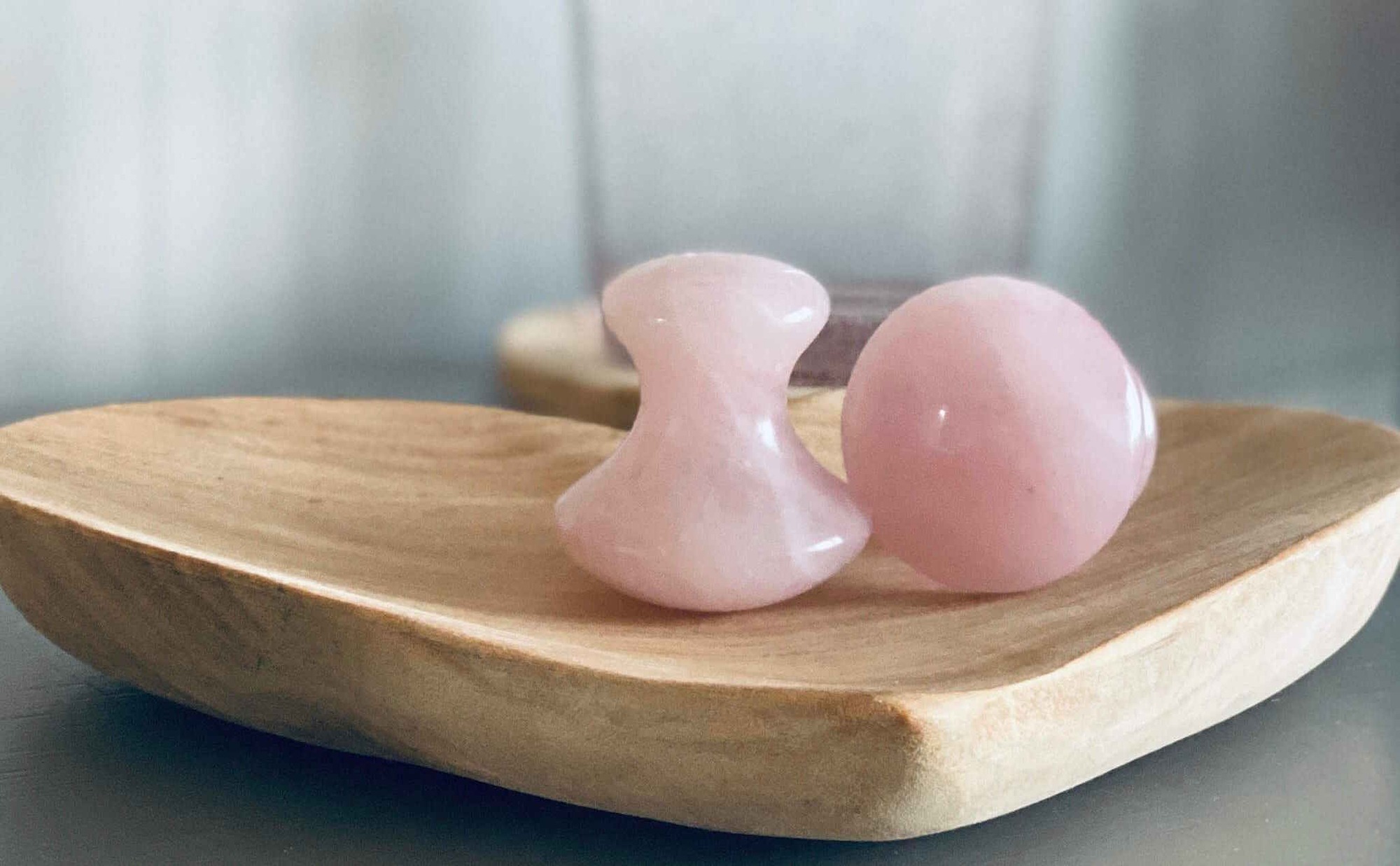 Rose quartz facial tools on wood tray, symbolizing natural, soothing skincare at Lucy's Facials in Somerset.