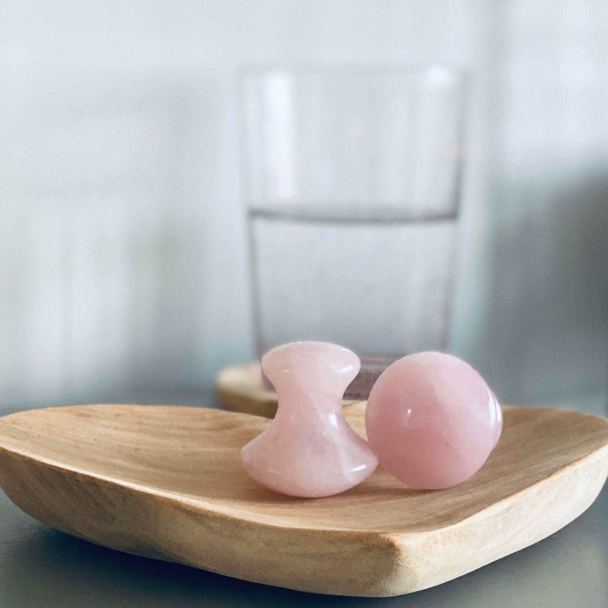 Rose quartz facial tools on wood tray, symbolizing natural, soothing skincare at Lucy's Facials in Somerset.