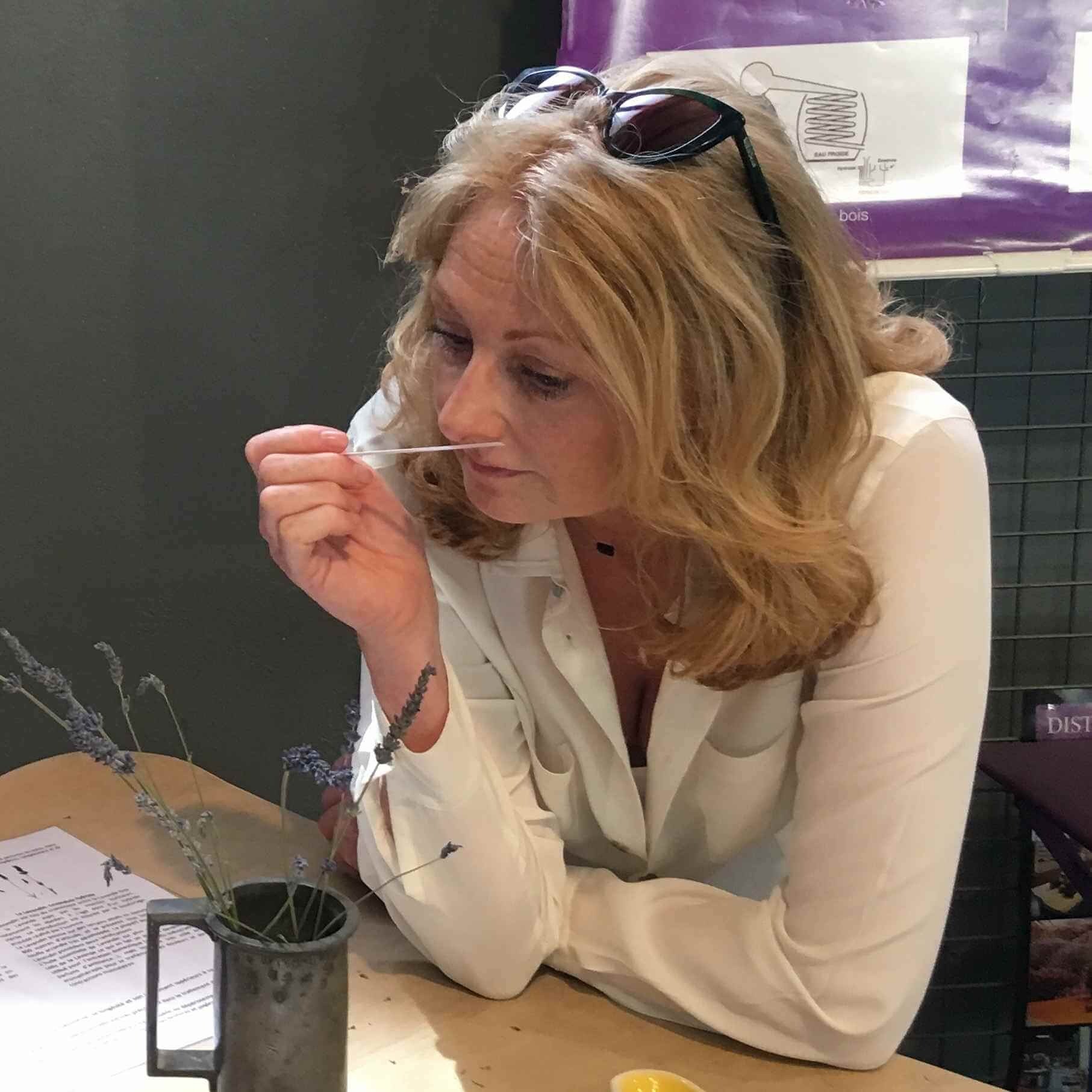 Lucy smelling a mouillette (scent strip) at a Lavender Distillery in France, reflecting her love of aromatherapy.