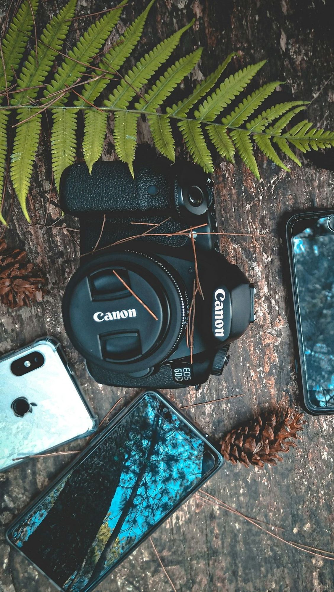 black canon dslr camera with three smartphones