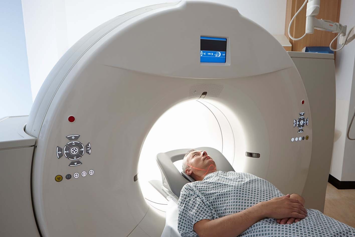 The CT scanner is a large ring that moves around part of your body as you lie on a flat bed.