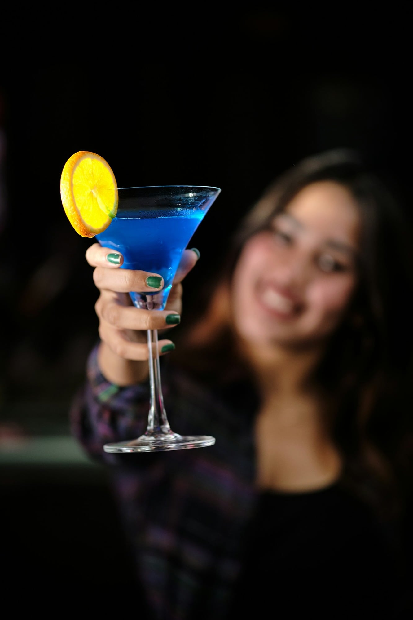 a-woman-holding-a-blue-cocktail-in-her-hand-cXKMlLCgCrw.jpg