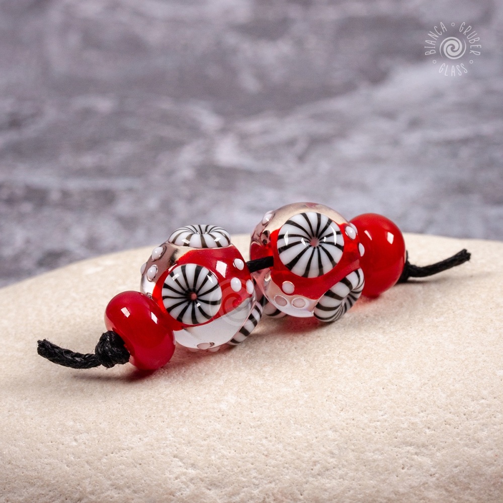 Red bead pair of round encased beads with black and white murrini