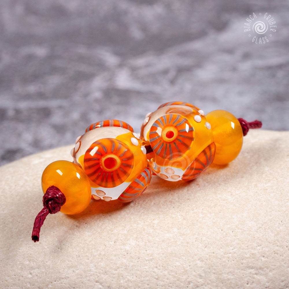 Warm yellow cored, clear encased beads with orange murrini raised decoration