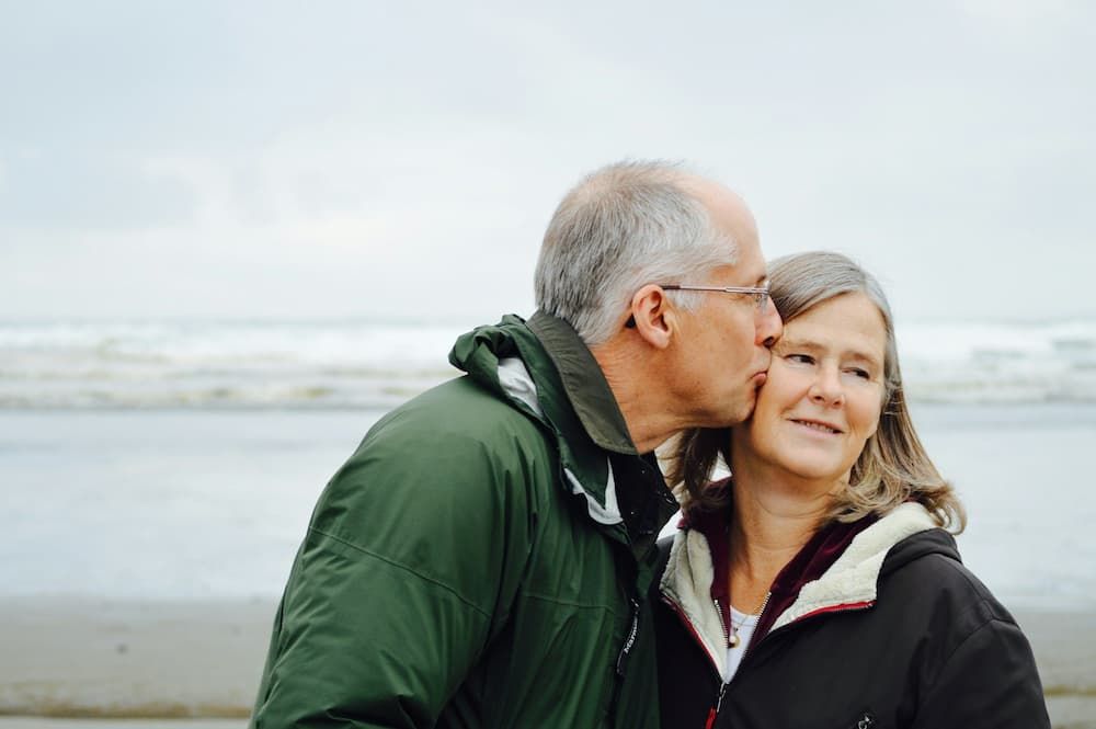 Couple kissing by the ocean, representing peace of mind for the future.
