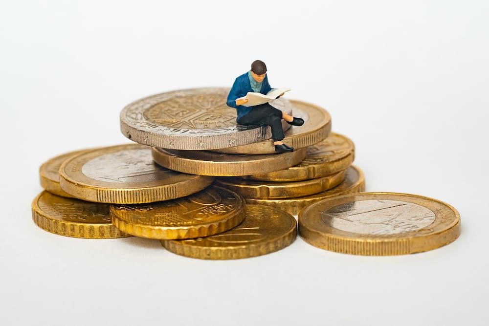 man reading book on a pile of coins