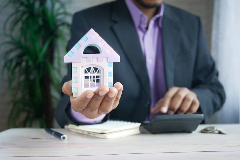 man holding miniature model house in palm of hand