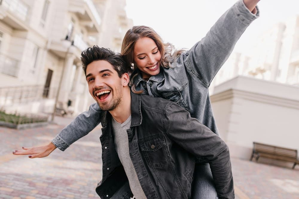 man giving woman piggybank both smiling