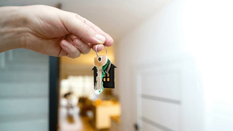 First time buyer's hand holding a new house key after successful mortgage completion.