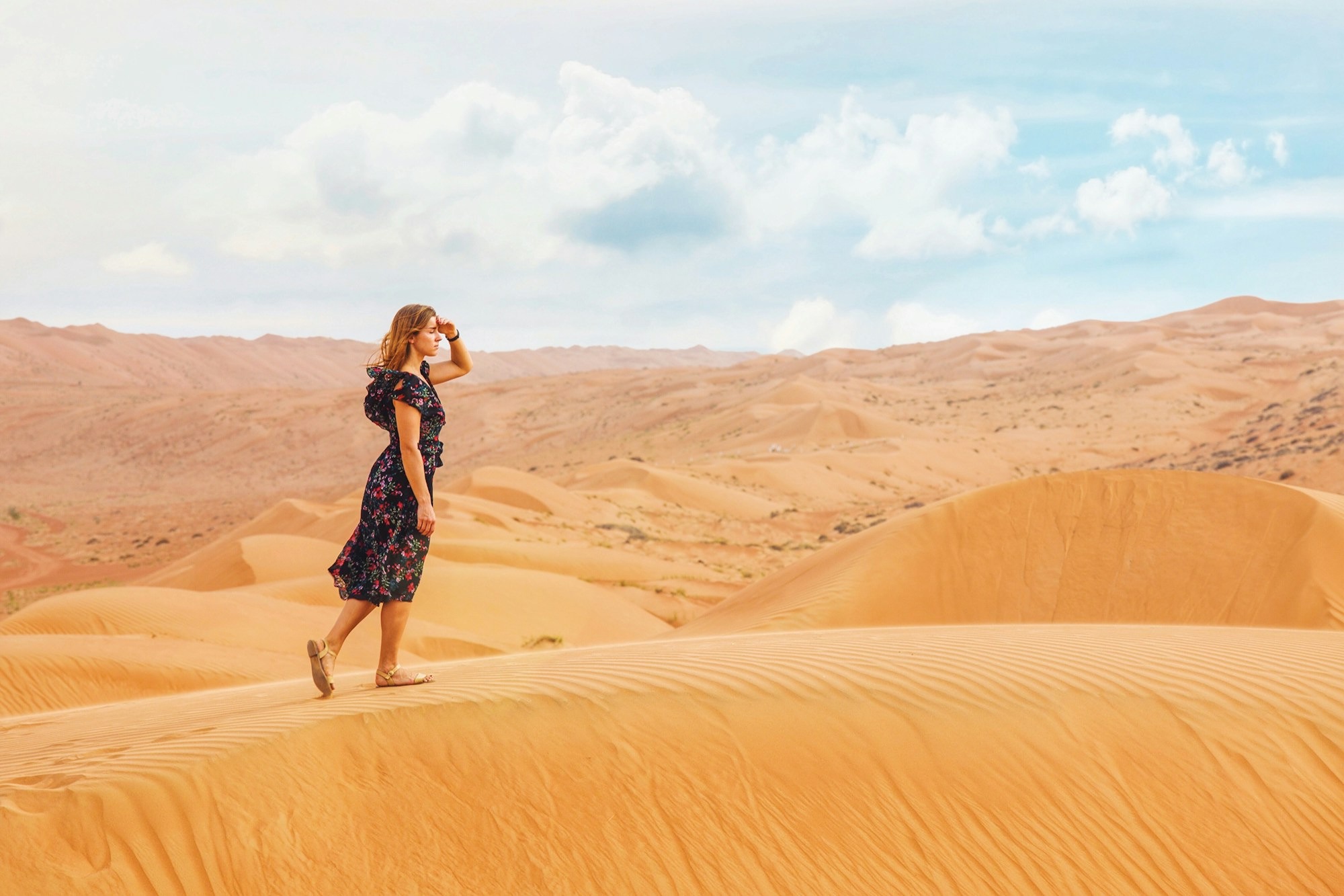 Image of a woman walking across sand dunes