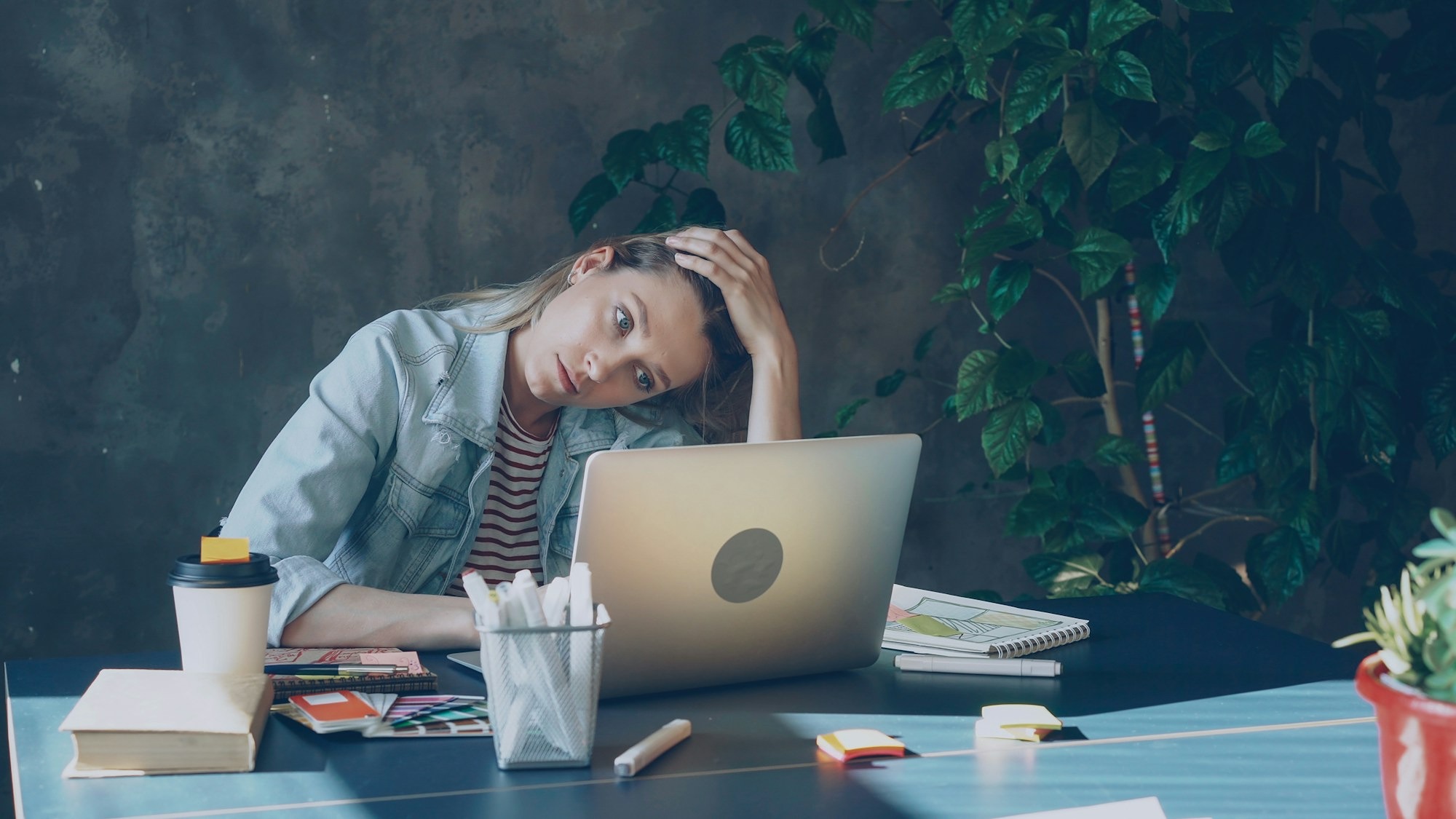 woman at her desk with her head resting on one hand