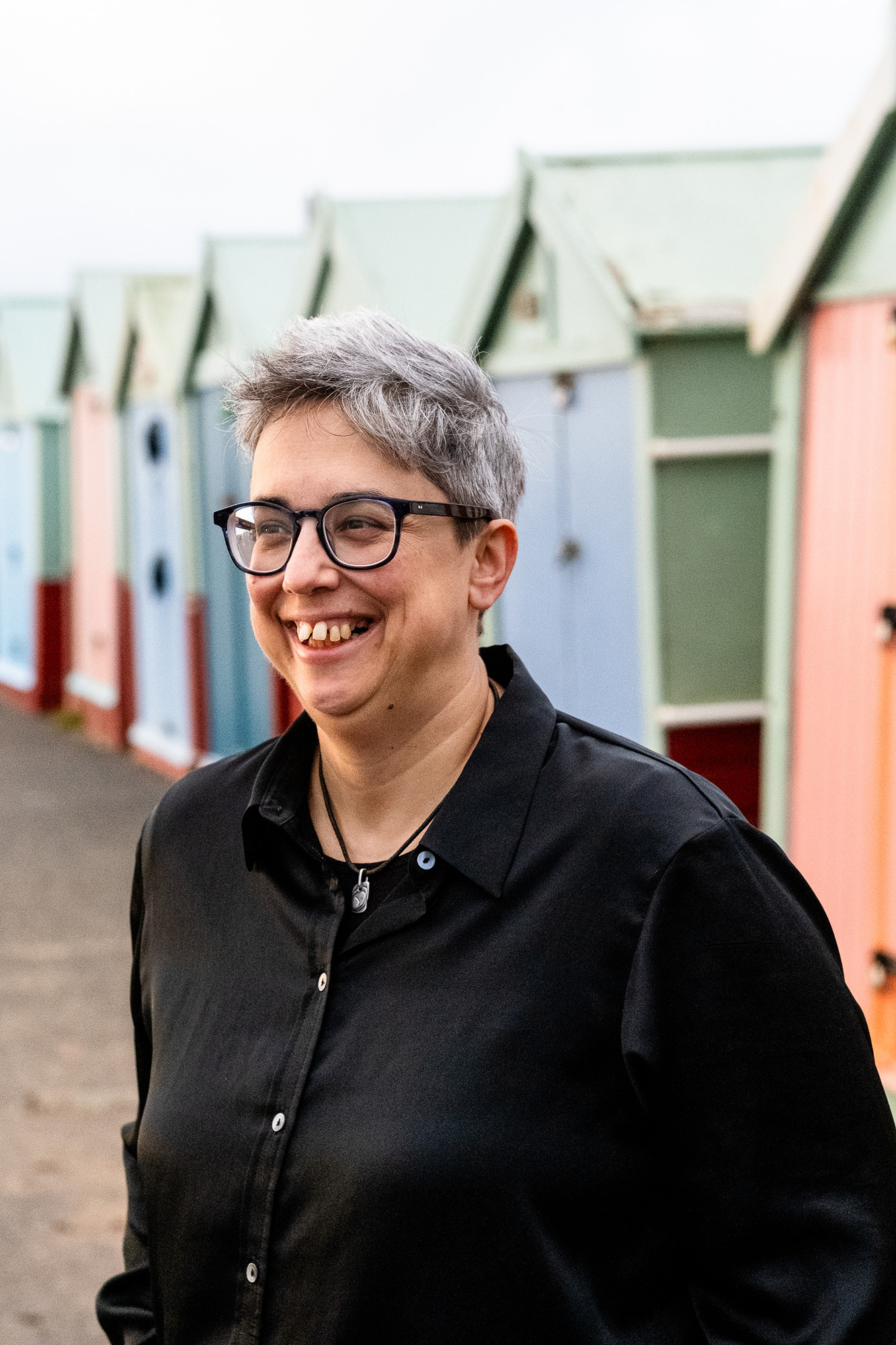 Louise Tondeur middle aged white woman in glasses in front of beach huts