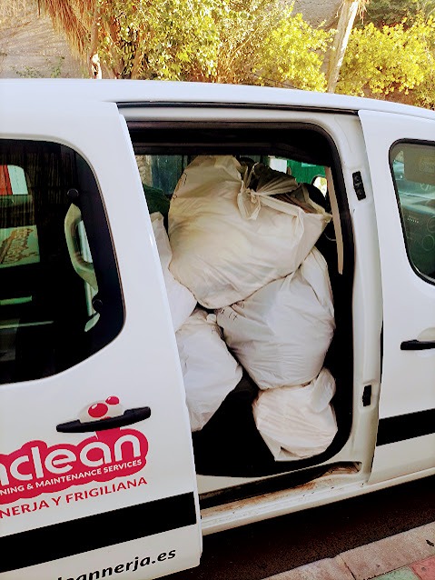 The side door of a white Dreamclean service van parked on a street, filled with large white laundry or cleaning supply bags, showcasing the company logo and contact details.
