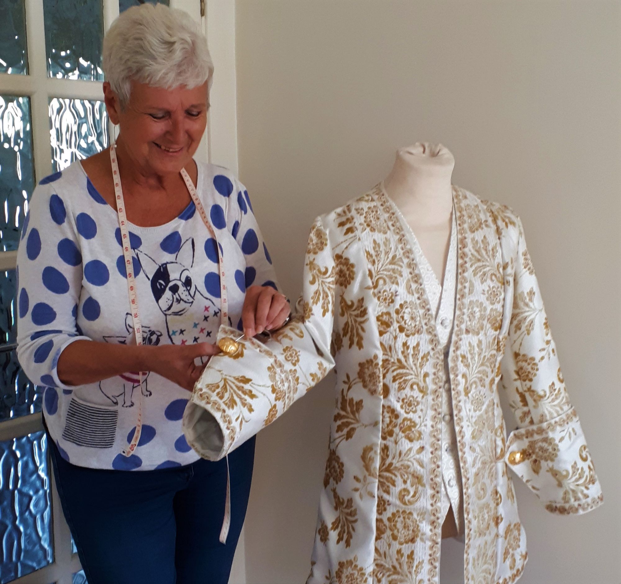 MArilyn, volunteer sews button to sleeve of home-made 18th c jacket